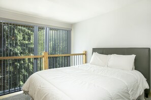 Relax in this serene bedroom with a large bed and peaceful views of the surrounding trees.