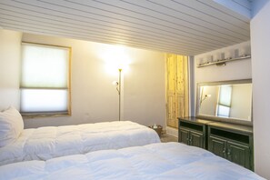 A bedroom with two beds, a wooden wardrobe, a mirror, and a floor lamp. - Contemporary Alpine Condo, Just Steps to Complimentary In-Town Shuttle (Vail)