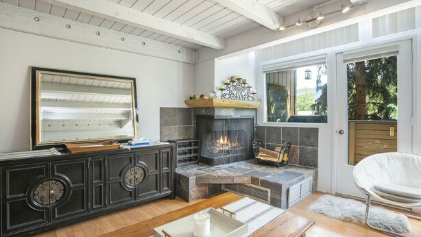 Een moderne woonkamer met een open haard, een grote spiegel en een witte stoel.