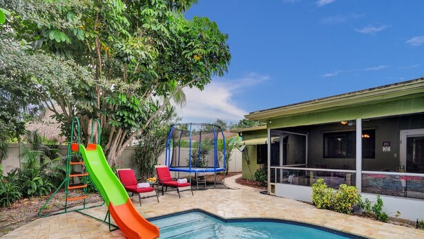 A swimming pool with a slide, a trampoline, and lounge chairs. - Heated Pool-Family Villa 7 Min to Beach, BBQ (Deerfield Beach)