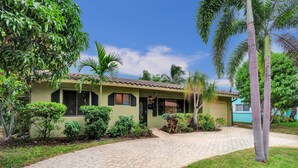 A house with a paved driveway, surrounded by lush greenery and palm trees. - Heated Pool-Family Villa 7 Min to Beach, BBQ (Deerfield Beach)