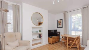 Un salon moderne avec un canapé, un téléviseur, une table en bois et une bibliothèque.