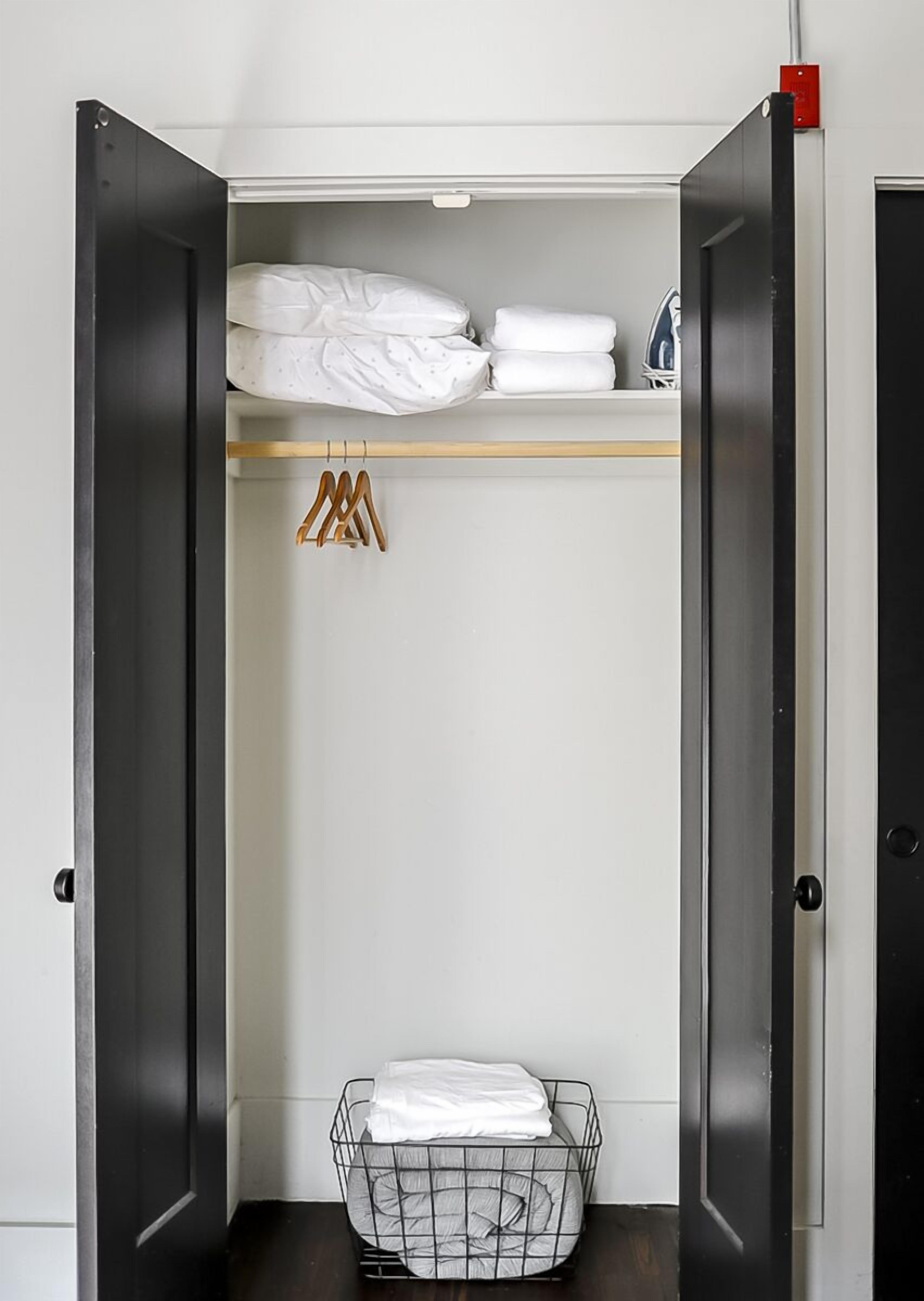 A walk-in closet with a hanging rack, shelves, and a wire basket.