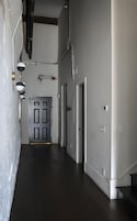 A hallway with a dark floor, a door with a handle, and a light switch on the wall.