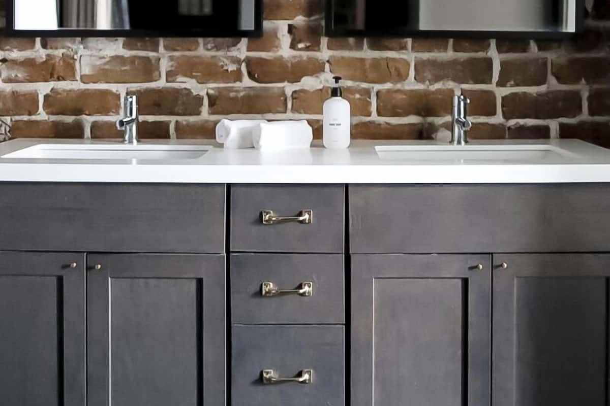 A bathroom with a double sink, dark cabinets, and a mirror above the sink.