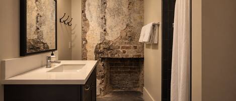 A bathroom with a stone wall, a sink, and a towel rack.
