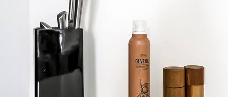 Eine Küchenarbeitsplatte mit einem Messerblock, einer Olivenölflasche und zwei Salz- und Pfefferstreuern aus Holz.