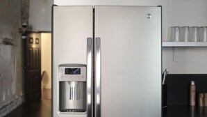 A stainless steel refrigerator with a water dispenser, a black trash bin, and a black countertop. - The Grant by Black Swan (Savannah)