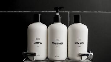 Three bottles of public goods shampoo, conditioner, and body wash on a metal shelf.