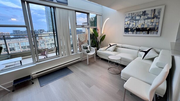 Uma sala de estar moderna com uma janela grande, um sofá branco, uma mesa pequena e um quadro na parede.
