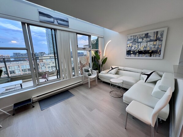 Relax in this stylish living room with a city view, featuring a sofa, coffee table, and modern artwork.