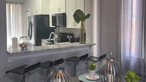 Una cocina moderna con armarios blancos, un refrigerador de acero inoxidable y un microondas.
