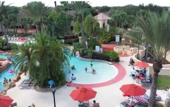 Un área de piscina con varias piscinas, palmeras y sombrillas.