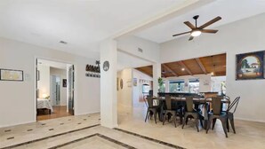 A spacious living area with a dining table and chairs, a ceiling fan, and a view of the kitchen. - Lakefront Resort Villa - Heated Infinity Pool & 8-Seat Spa - Kayaks - 4BR (Mesa)