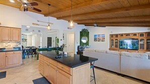 A spacious kitchen with wooden cabinets, a central island, and a dining area with chairs. - Lakefront Resort Villa - Heated Infinity Pool & 8-Seat Spa - Kayaks - 4BR (Mesa)