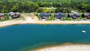 Une propriété au bord du lac comprenant plusieurs maisons, une plage de sable et un bateau.