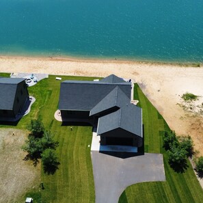 Une vue aérienne d’un quartier résidentiel avec des maisons, une plage et un ciel dégagé.