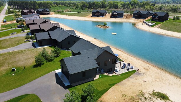 Une propriété au bord du lac comprenant plusieurs chalets, une plage de sable et un quai pour bateaux.