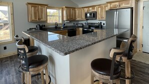 Une cuisine moderne dotée d’un grand îlot central, de meubles en bois et de tabourets de bar.