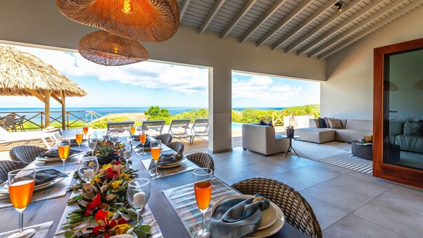 A dining area with a table set for six, overlooking a scenic view. - Brand new luxurious villa with bay and mountain view (Curaçao)