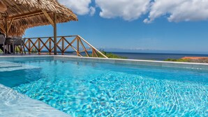 A clear blue pool with a wooden deck and chairs, overlooking the ocean. - Brand new luxurious villa with bay and mountain view (Curaçao)