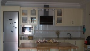 A kitchen with a refrigerator, microwave, and wooden dining table with chairs. - MODERN APARTMENT, SPACIOUS AND WITH LARGE TERRACE (Lomo Quiebre)