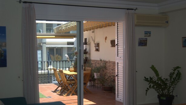 A room with a sliding glass door leading to an outdoor patio area with a table, chairs, and potted plants. - MODERN APARTMENT, SPACIOUS AND WITH LARGE TERRACE (Lomo Quiebre)