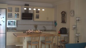 A kitchen with a central island, wooden chairs, a microwave, and a clock on the wall. - MODERN APARTMENT, SPACIOUS AND WITH LARGE TERRACE (Lomo Quiebre)