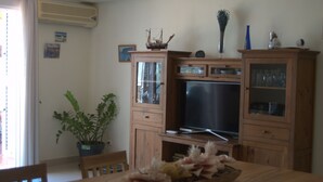 A living room with a wooden cabinet, a television, and a dining table with a centerpiece. - MODERN APARTMENT, SPACIOUS AND WITH LARGE TERRACE (Lomo Quiebre)