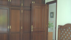 A bedroom with a bed, wooden wardrobe, and a potted plant. - MODERN APARTMENT, SPACIOUS AND WITH LARGE TERRACE (Lomo Quiebre)