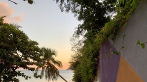 A concrete staircase leading to a beach with a view of the ocean and a wall with graffiti.