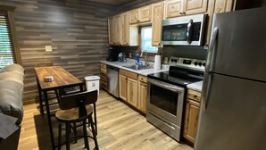 Une cuisine moderne avec des meubles en bois, des appareils en acier inoxydable et un coin repas comprenant une table et des chaises.
