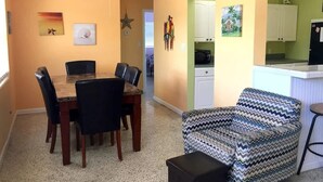 Een eetruimte met een houten tafel en stoelen, een plafondventilator en wanddecoraties, waaronder een ster en een schilderij.
