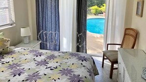 Een slaapkamer met een bed, een stoel, een tafel en uitzicht op een zwembad.