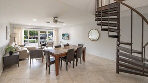 Un intérieur moderne comprenant un coin repas, un canapé, un ventilateur de plafond et un escalier en colimaçon.