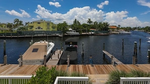 Un port de plaisance avec des bateaux amarrés, une terrasse en bois et, au fond, un bâtiment à la façade jaune.