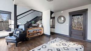 A modern interior with a staircase, a black leather chair, a wooden bookshelf, and a patterned rug. - Restful Retreat with Panoramic Views, Hot Tub, and Centrally Located to Deadwood (Lead)