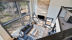 A modern loft-style living area with a large window, a fireplace, and a staircase. - Restful Retreat with Panoramic Views, Hot Tub, and Centrally Located to Deadwood (Lead)
