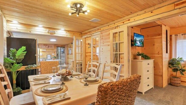 Un interior de madera con una mesa de comedor para cuatro personas, rodeada de sillas de mimbre.