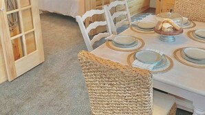 Interior de una cabaña de madera con comedor, cama y baño.
