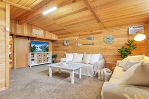 Um interior de madeira com um sofá, uma mesa de centro e um armário branco com caixas organizadoras.