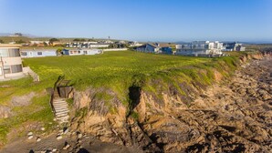 Una zona residencial costera con casas, un campo cubierto de césped y una orilla rocosa.