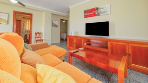 A living room with a large orange sofa, a wooden coffee table, and a flat-screen TV mounted on the wall. - Cubo's Casa Rio Grande / private pool / rural (Guaro)