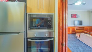 A compact kitchen with a refrigerator, microwave, and oven. - Cubo's Casa Rio Grande / private pool / rural (Guaro)
