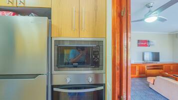 A compact kitchen with a refrigerator, microwave, and oven.