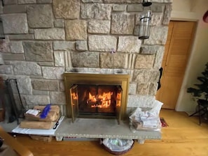 Cozy fireplace with a warm fire, surrounded by a traditional wooden floor and a door leading to a welcoming space.