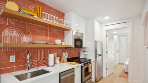 Una cocina moderna con armarios blancos, un lavamanos de acero inoxidable y un horno empotrado.