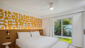 Una habitación de hotel moderna con una cama grande, una mesita de noche, un ventilador de techo y vistas al exterior.