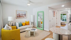 Una sala de estar moderna con un sofá, un sillón amarillo, una mesita de centro y un espejo con marco verde.