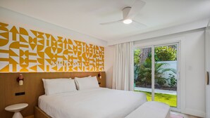A modern hotel room with a large bed, a bedside table, a ceiling fan, and a view of the outdoors. - Mello on the Beach - Shore Enuff (Holmes Beach)
